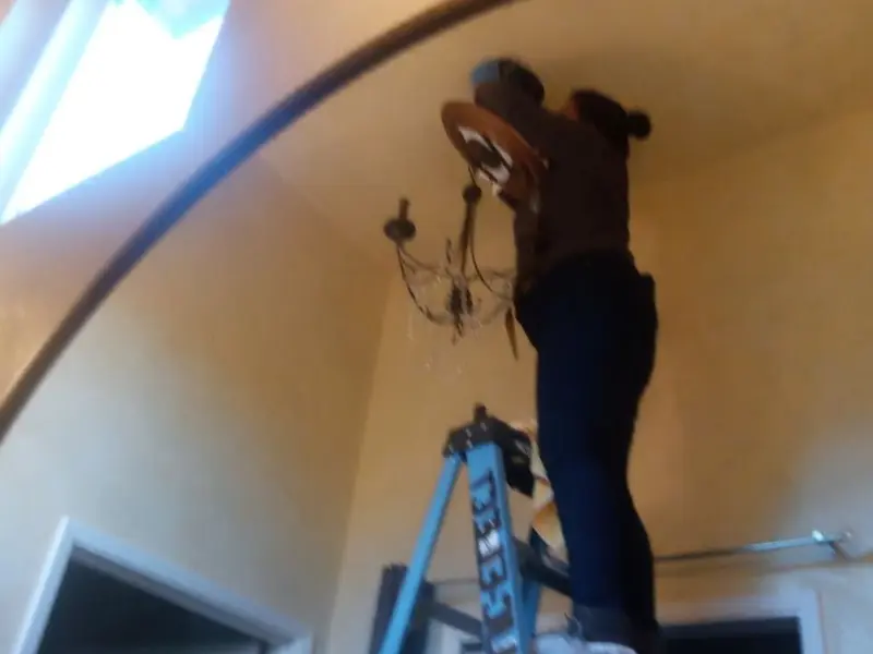 Electrician installing a chandelier in a Dry Ridge residence